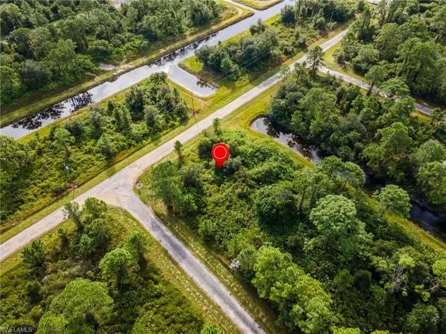 Aerial view of property's location featuring a nearby body of water and a tree filled landscape