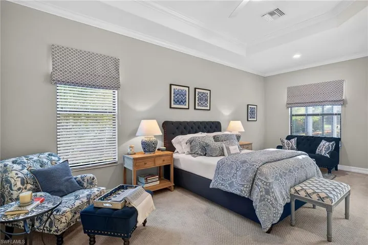 Carpeted bedroom featuring ornamental molding, a tray ceiling, a ceiling fan, and recessed lighting