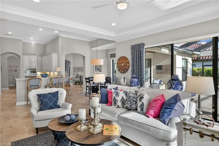 Living area featuring arched walkways, stone tile floors, recessed lighting, ornamental molding, and a ceiling fan
