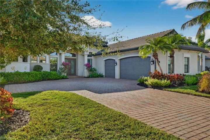 View of front of home with decorative driveway, a garage, stucco siding, a tiled roof, and french doors