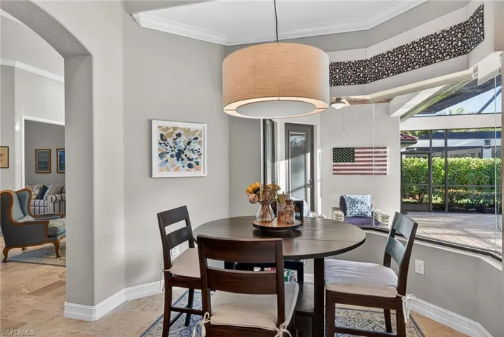 Dining area with crown molding, stone tile flooring, arched walkways, and a sunroom