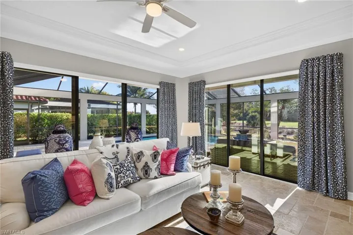 Living area with a sunroom, stone tile floors, ceiling fan, plenty of natural light, and ornamental molding