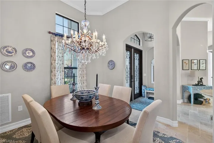 Dining room with arched walkways, ornamental molding, healthy amount of natural light, a chandelier, and a high ceiling