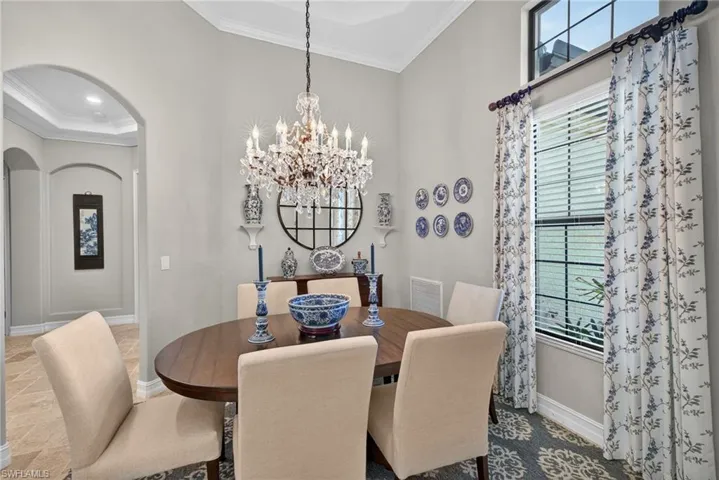 Dining room featuring a chandelier, arched walkways, ornamental molding, and plenty of natural light