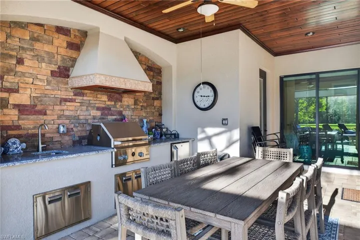 View of patio with outdoor dining space, ceiling fan, and exterior kitchen