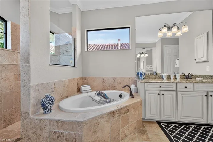 Bathroom with ornamental molding, vanity, a bath, healthy amount of natural light, and walk in shower
