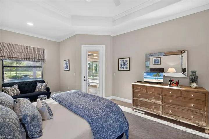 Bedroom with access to exterior, light colored carpet, ornamental molding, a tray ceiling, and ceiling fan