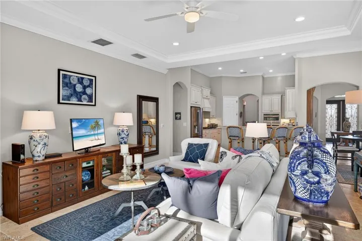 Living room with recessed lighting, arched walkways, ceiling fan, and crown molding