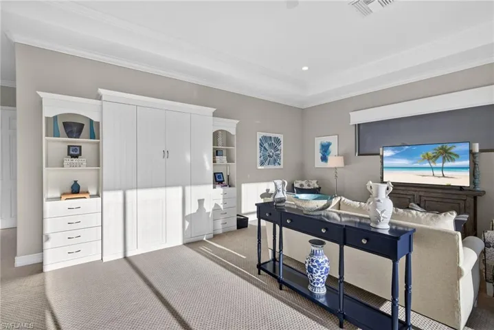 Carpeted bedroom featuring ornamental molding, recessed lighting, and a raised ceiling