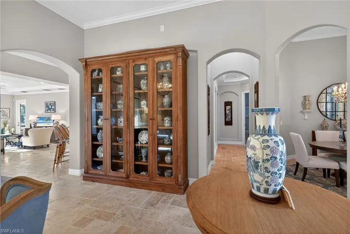 Hall featuring ornamental molding, stone tile flooring, and arched walkways