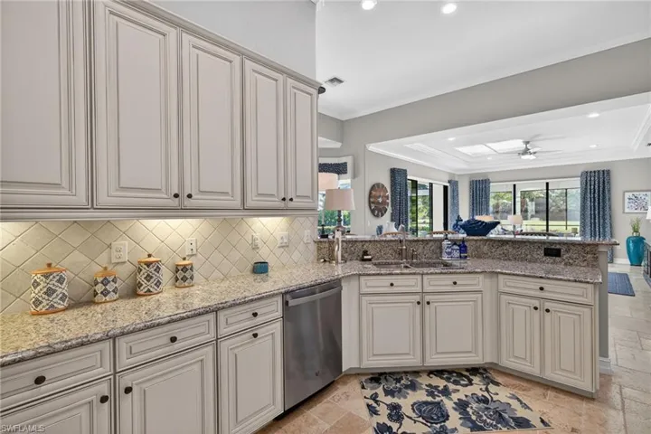 Kitchen featuring light stone counters, stainless steel dishwasher, stone tile flooring, recessed lighting, and a peninsula