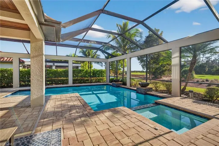 View of pool featuring a pool with connected hot tub, a lanai, a sunroom, and a patio