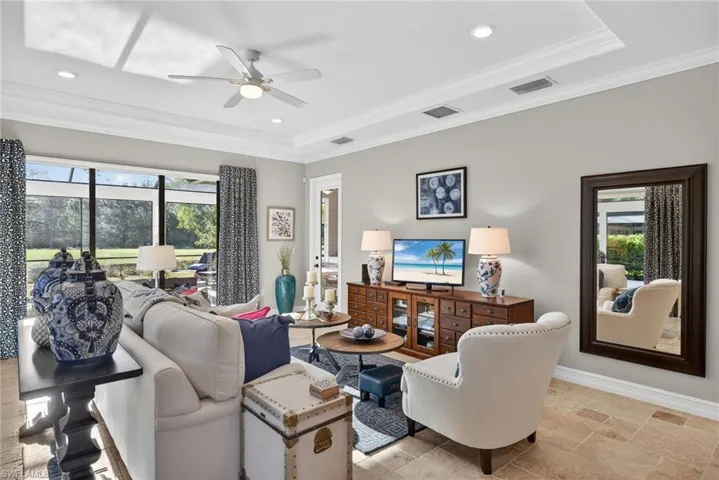 Living area with stone tile floors, ceiling fan, crown molding, a tray ceiling, and recessed lighting