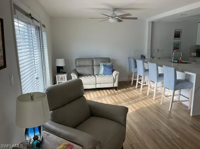 Living room with baseboards, light wood-style flooring, and a ceiling fan