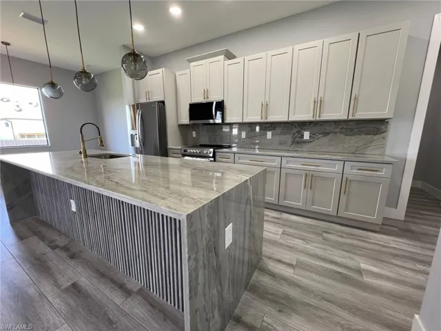 Kitchen with appliances with stainless steel finishes, sink, an island with sink, and light wood-type flooring