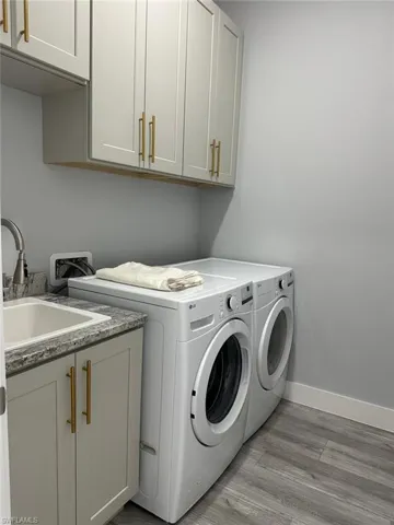 Laundry area featuring sink, cabinets, light wood-type flooring, and independent washer and dryer