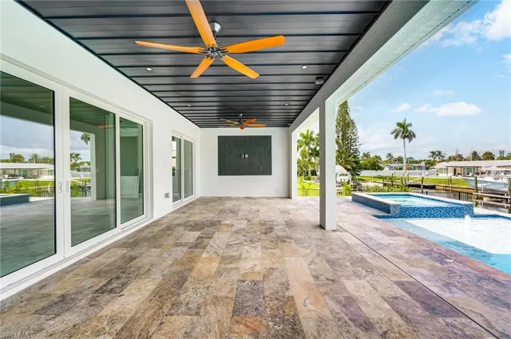 View of patio / terrace featuring a pool with connected hot tub, a ceiling fan, and a water view