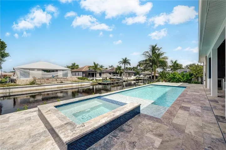 View of pool featuring a patio, a water view, a pool with connected hot tub, and a residential view