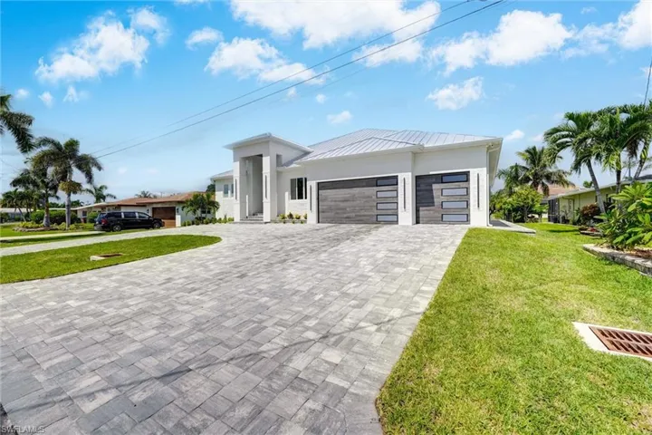 Contemporary house with a front yard, an attached garage, decorative driveway, a metal roof, and stucco siding