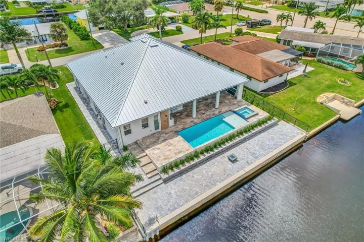 Aerial perspective of suburban area with a pool and a nearby body of water