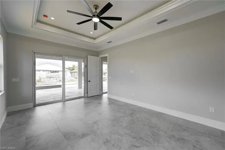 Empty room with a raised ceiling, ornamental molding, a ceiling fan, and recessed lighting