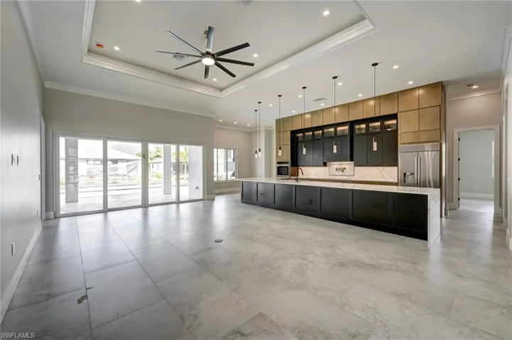 Unfurnished living room featuring crown molding, a tray ceiling, ceiling fan, and recessed lighting