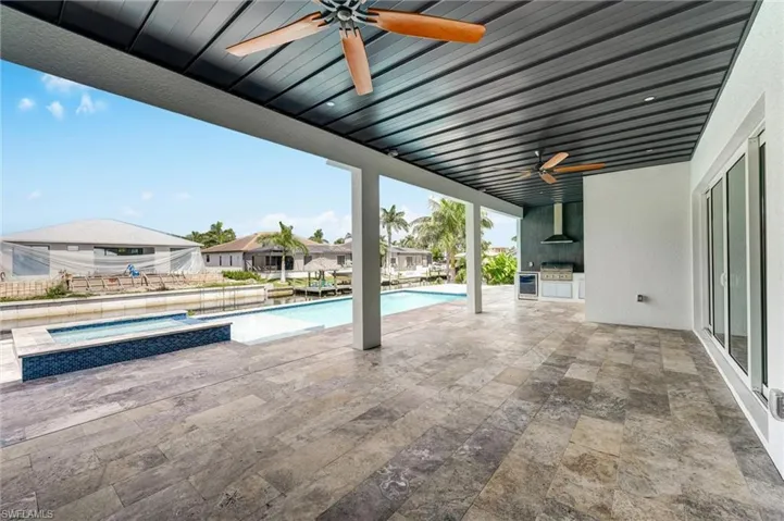 View of swimming pool featuring a patio, ceiling fan, a pool with connected hot tub, and exterior kitchen