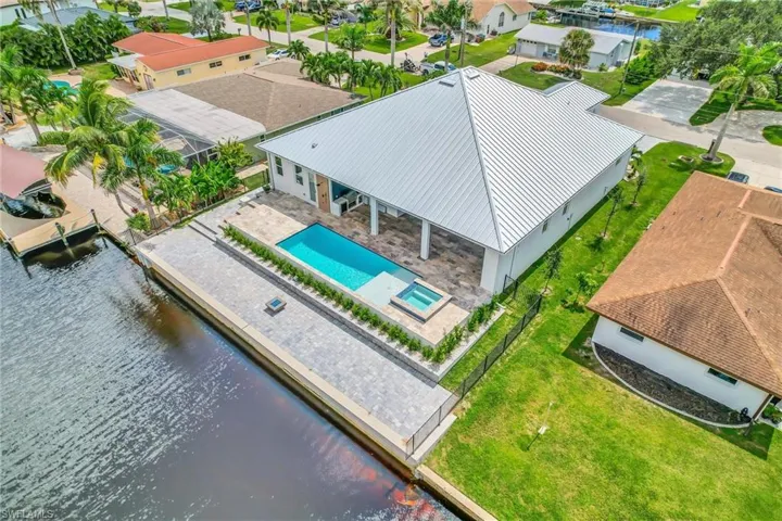 Aerial perspective of suburban area featuring a pool area and a nearby body of water
