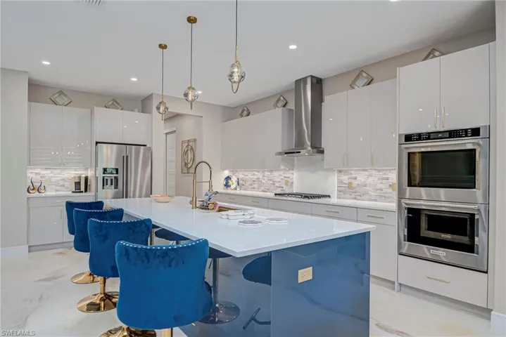 Kitchen with decorative light fixtures, stainless steel appliances, a breakfast bar, and white cabinetry
