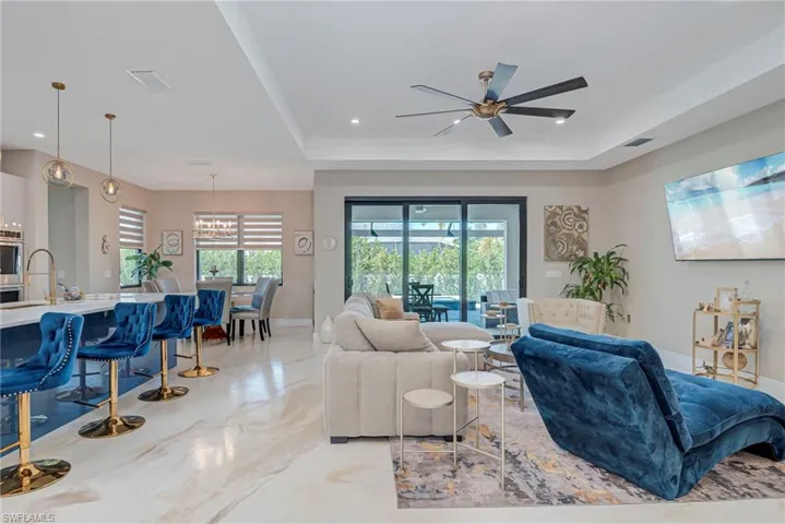 Living area with ceiling fan, plenty of natural light, and a raised ceiling