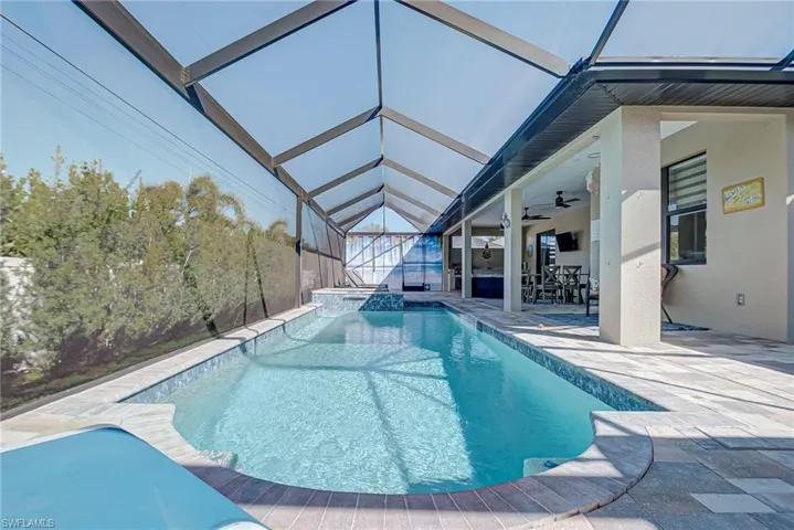 Relaxing pool / spa featuring a sunroom, a lanai, and a patio