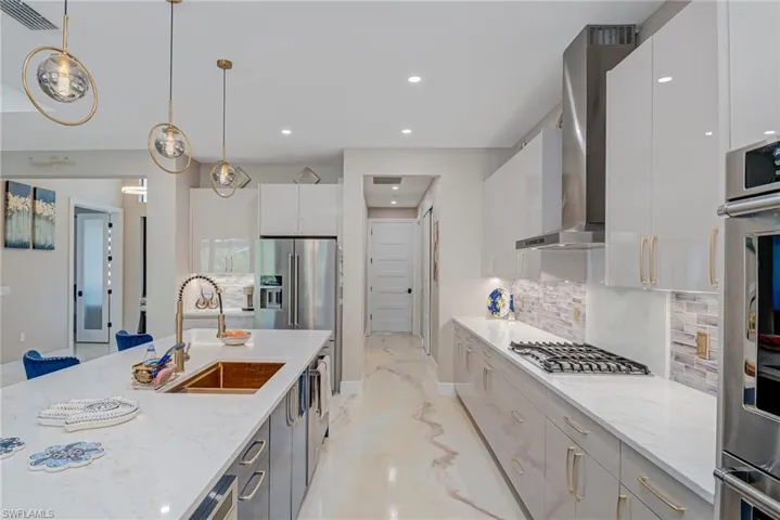 Kitchen featuring light stone counters, modern cabinets, decorative light fixtures, and decorative backsplash
