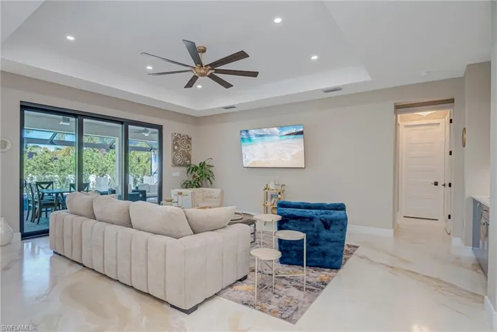 Living room featuring a ceiling fan, recessed lighting, and a raised ceiling