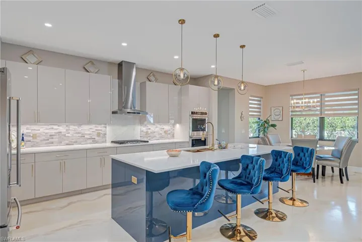 Kitchen with a breakfast bar, modern cabinets, white cabinetry, light stone counters, and backsplash