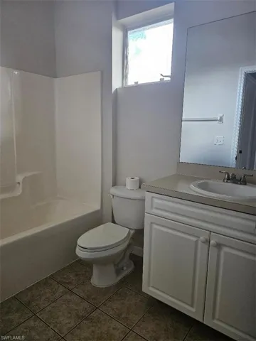 Bathroom featuring vanity, bathtub / shower combination, and dark tile patterned flooring