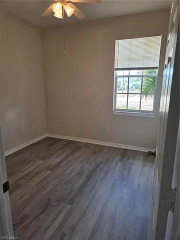 Empty room with dark wood finished floors and a ceiling fan