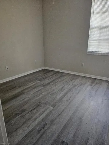 Unfurnished room featuring baseboards and dark wood-style floors