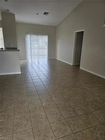 Empty room featuring light tile patterned floors and lofted ceiling