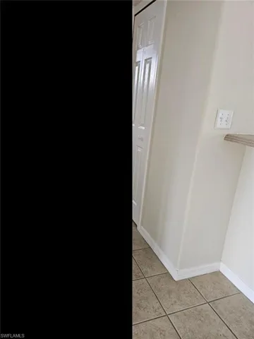Hallway with baseboards and light tile patterned floors
