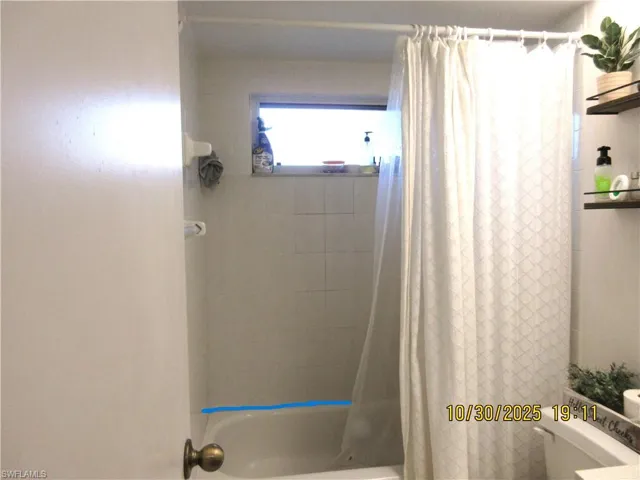 Full bath featuring shower / bath combo with shower curtain and toilet