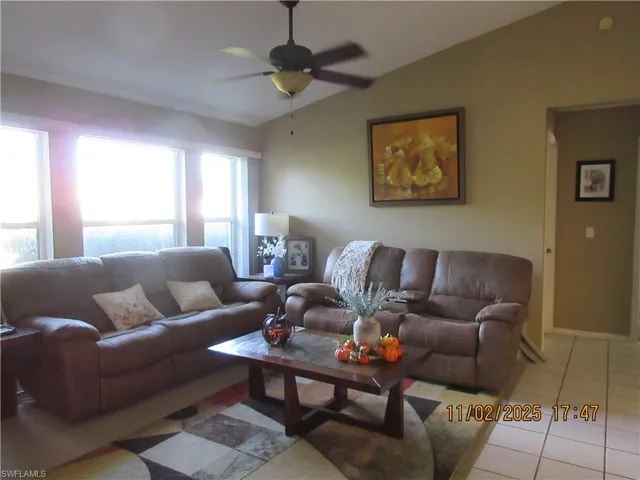 Living room featuring vaulted ceiling, tile patterned floors, and a ceiling fan