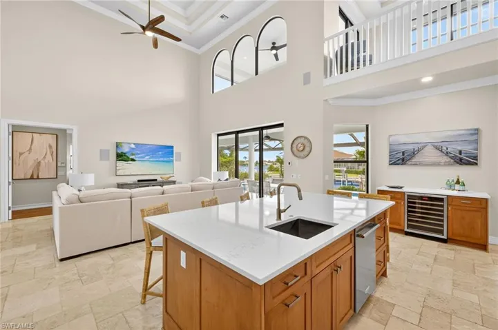 Kitchen with a high ceiling, ornamental molding, beverage cooler, stone tile flooring, and a ceiling fan