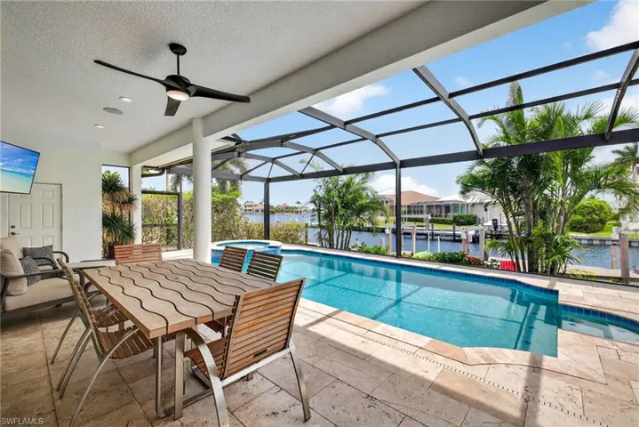View of swimming pool featuring a water view, a patio area, a pool with connected hot tub, a lanai, and ceiling fan