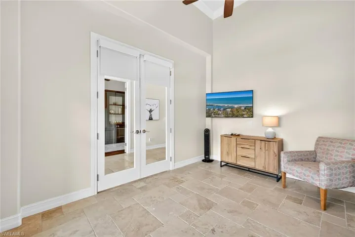 Sitting room with stone tile flooring, french doors, ceiling fan, and a high ceiling