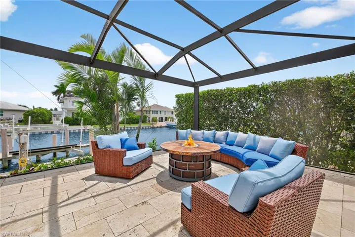 View of patio with a water view, an outdoor living space with a fire pit, glass enclosure, and a dock