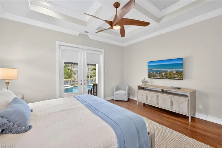 Bedroom with french doors, access to exterior, wood finished floors, coffered ceiling, and crown molding
