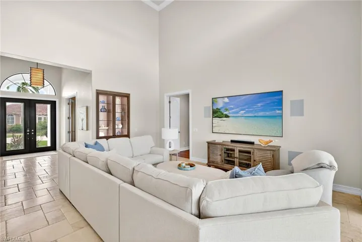 Living area with a towering ceiling, french doors, crown molding, and stone tile floors
