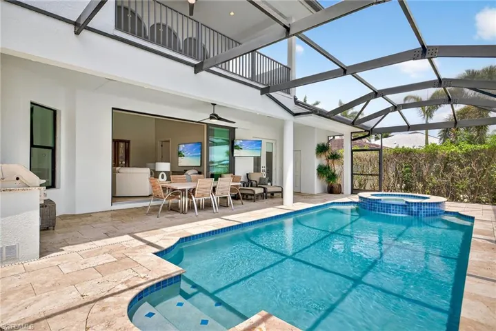 View of swimming pool with ceiling fan, a patio, a pool with connected hot tub, and glass enclosure