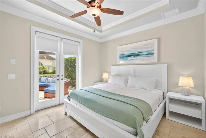Bedroom with access to exterior, crown molding, french doors, a tray ceiling, and stone tile flooring