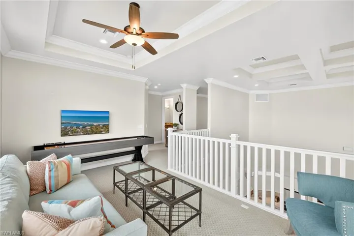Living room with crown molding, recessed lighting, ceiling fan, carpet flooring, and a raised ceiling